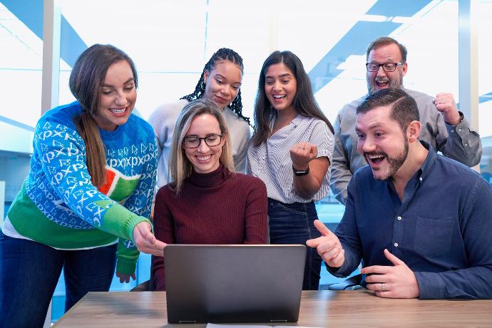 mannen en vrouwen zitten en staan terwijl ze naar de laptop staren